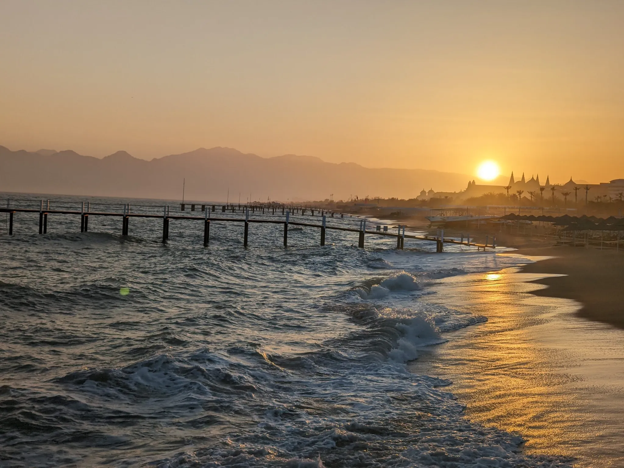 Evening sunlight crosses the waves and wet sand on the Lara coast near Antalya, Türkiye.