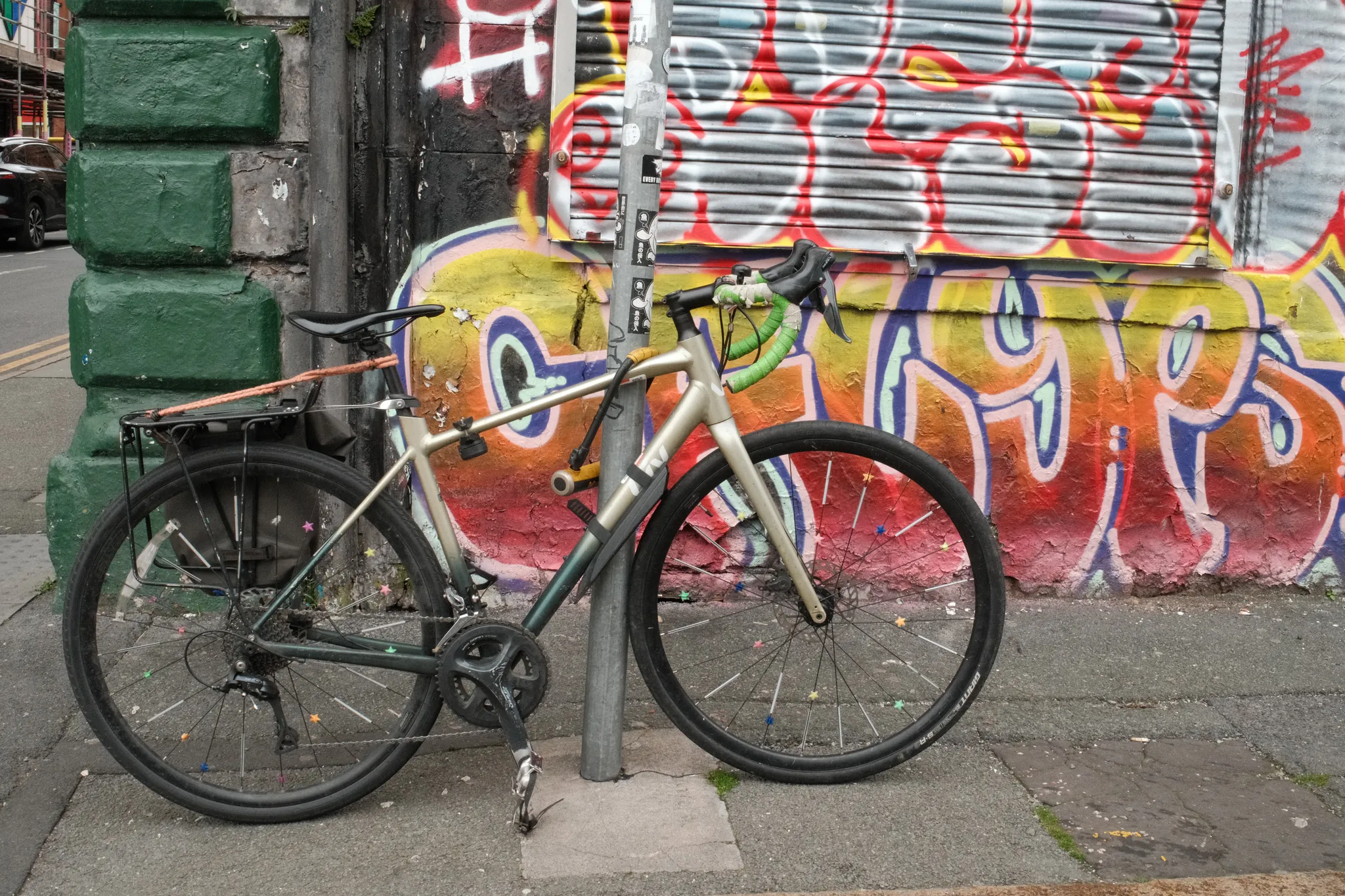 A bicycle leans against a brightly painted shutter and green doorway.