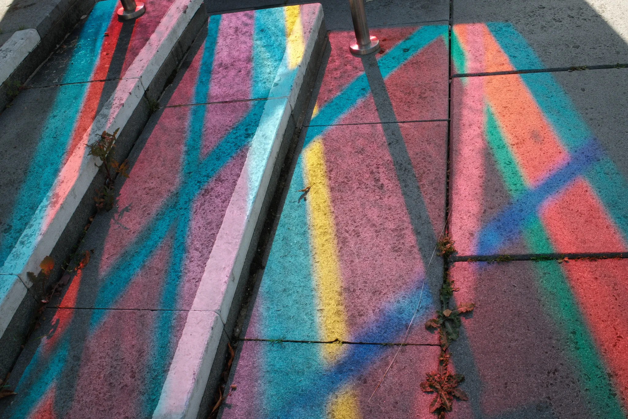 Vivid bands of light stretch over paving, steps and a handrail.
