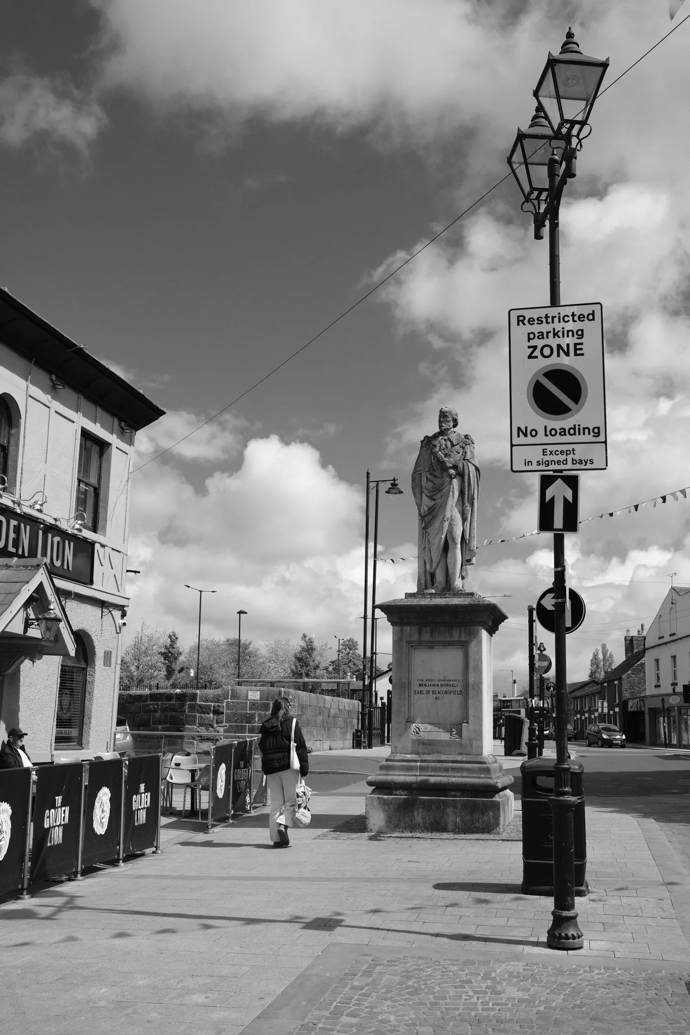 Benjamin Disraeli’s statue rises beside street signs and a lamp in Moor Street.