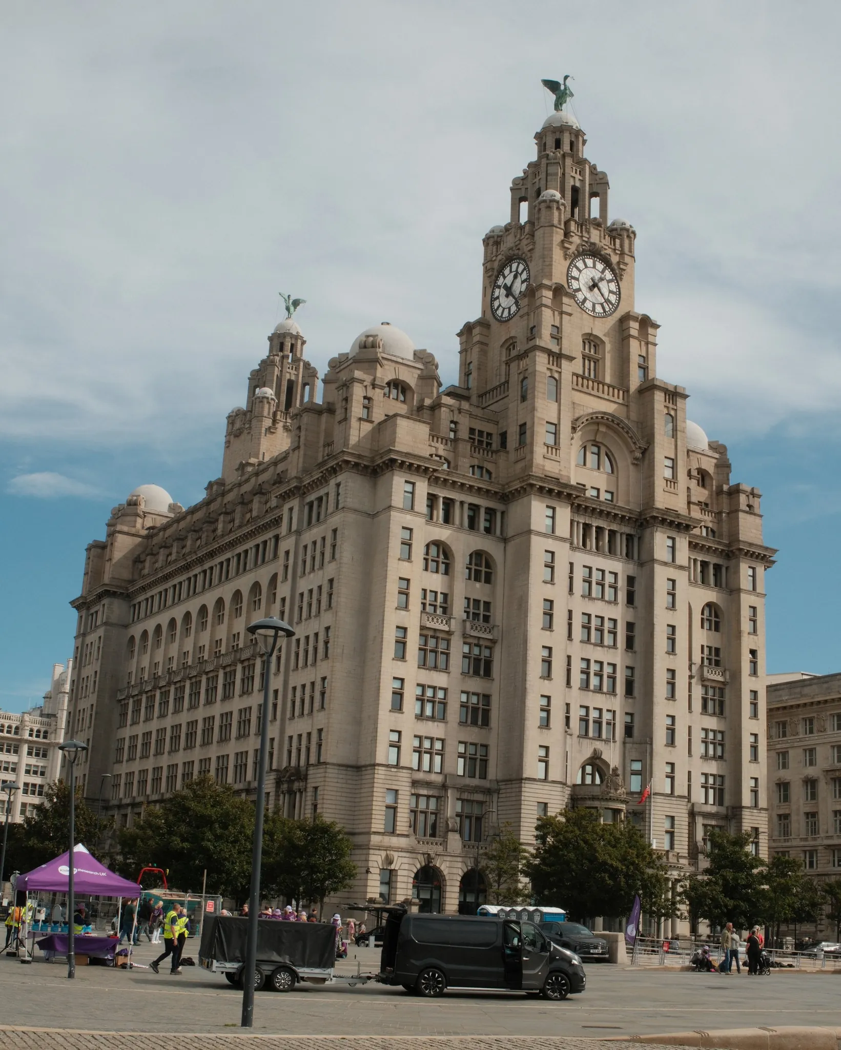 A colour street-level view of the Royal Liver Building and passing traffic.