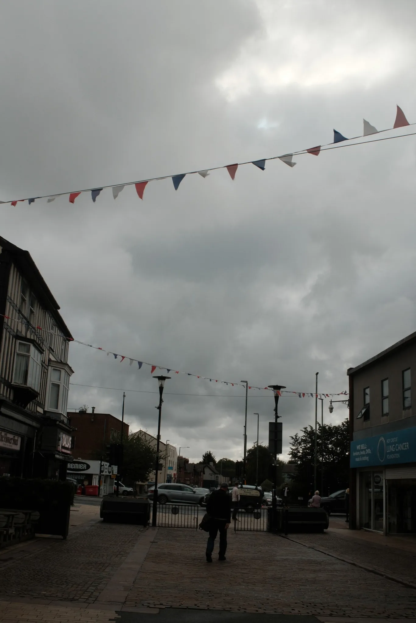 Bunting above a street under a heavy grey sky.