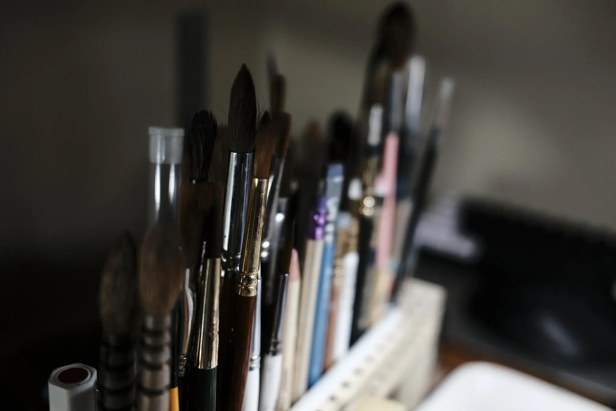Paintbrushes standing upright with softly blurred tools behind them.
