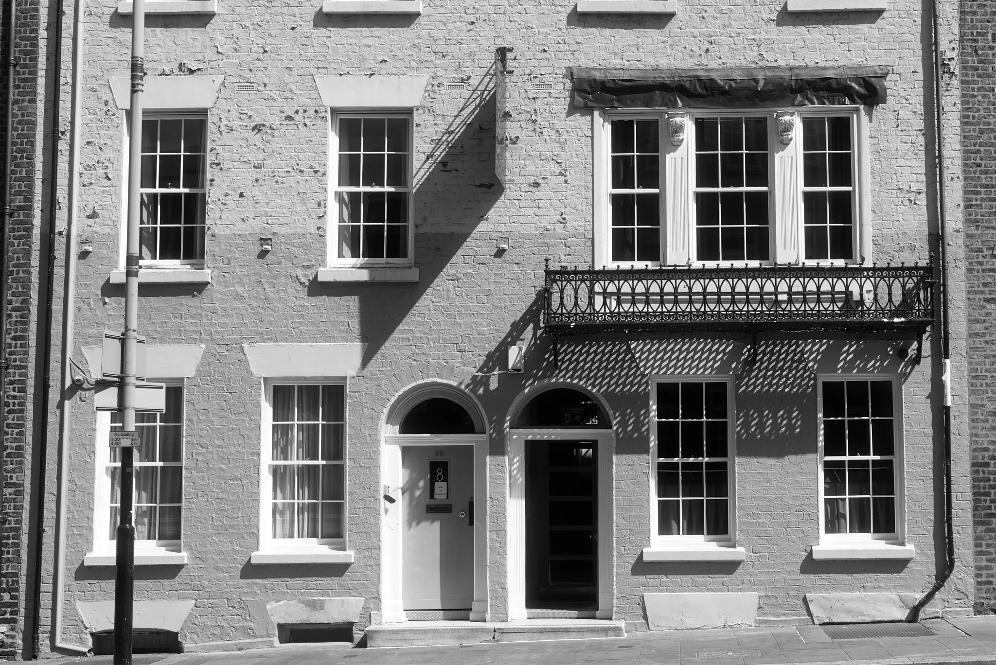 A brick facade with sash windows and a recessed doorway, in black and white.