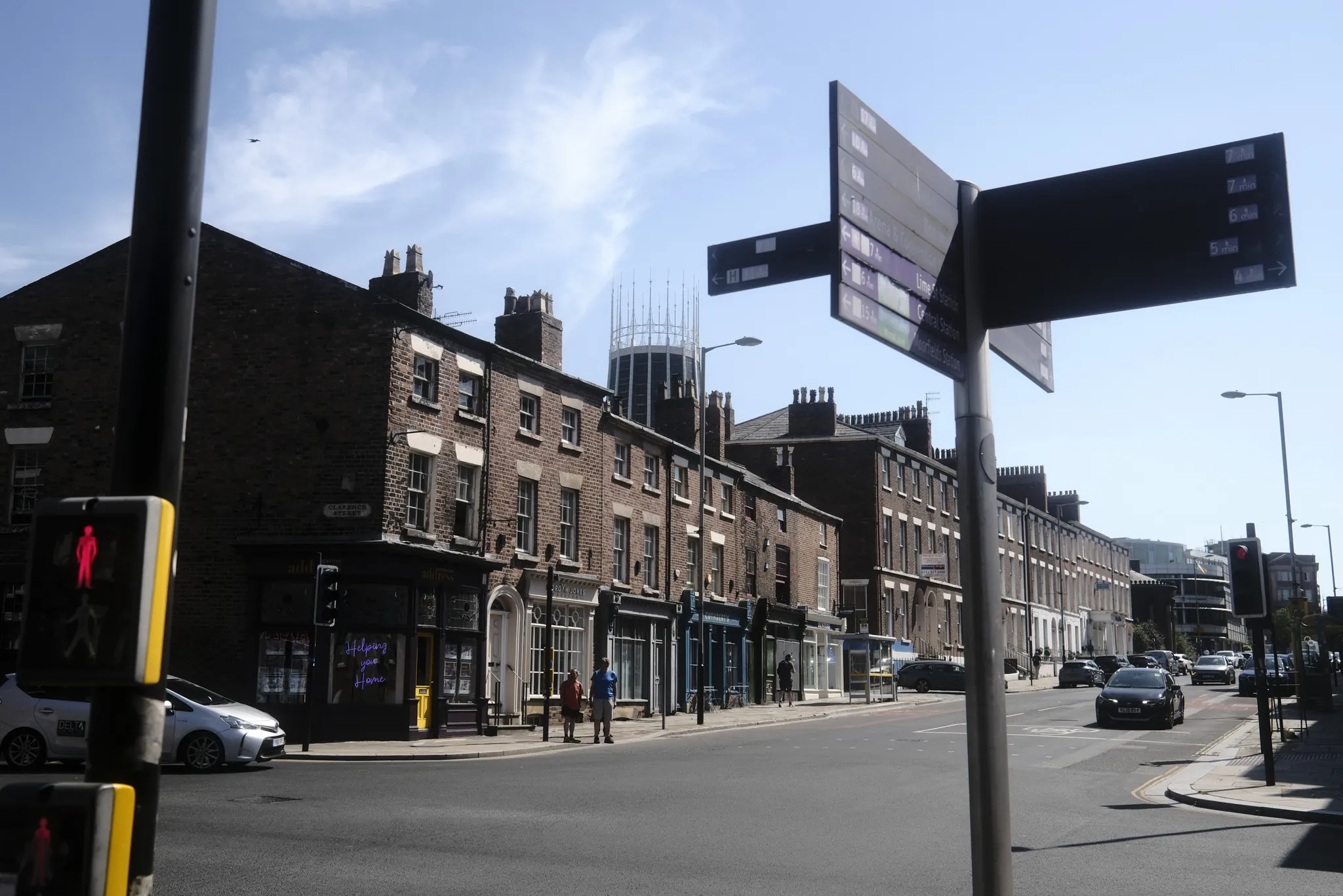 Street signs and brick buildings frame a Liverpool junction, with the Metropolitan Cathedral beyond.