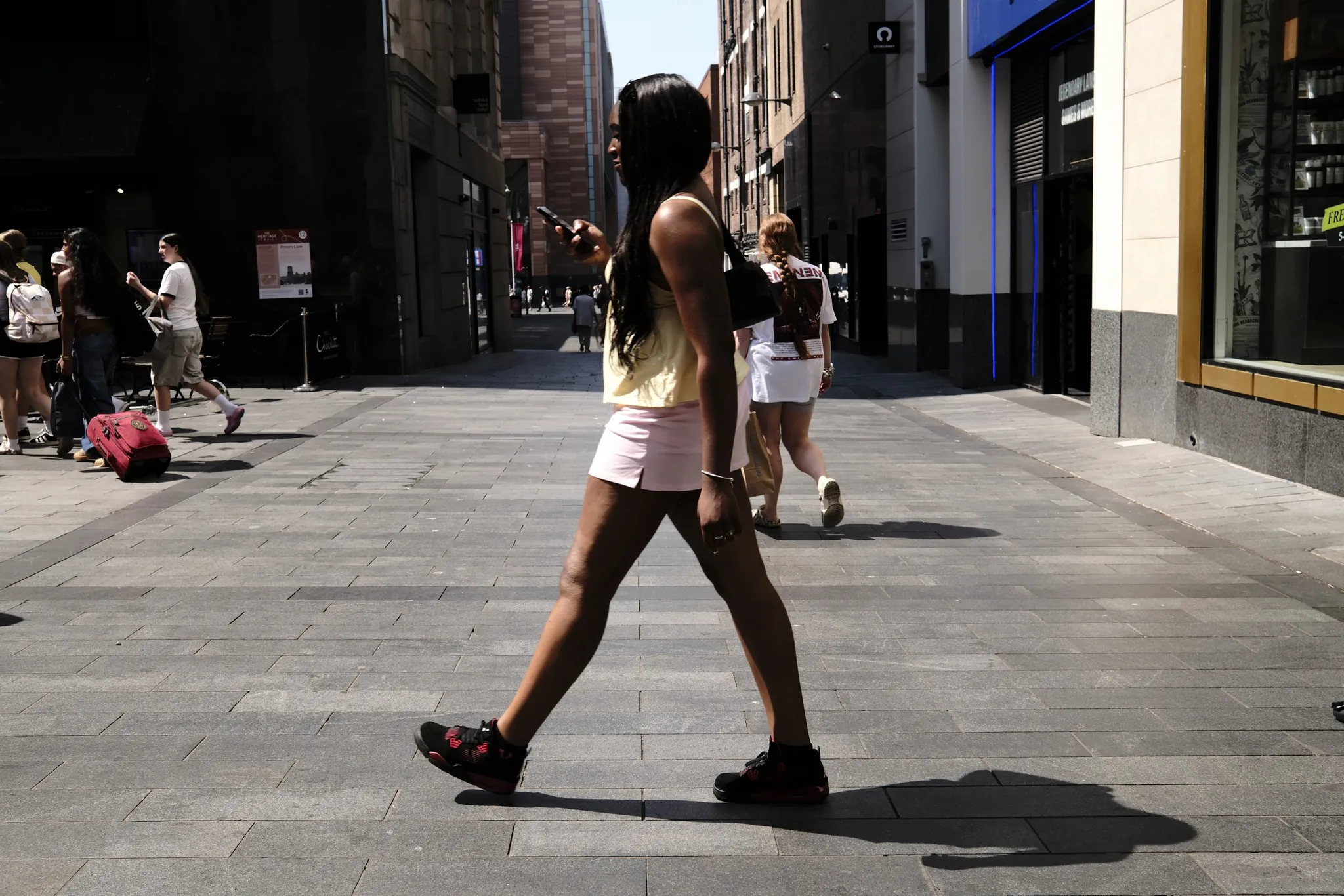 A pedestrian casting a strong shadow across a sunlit street.