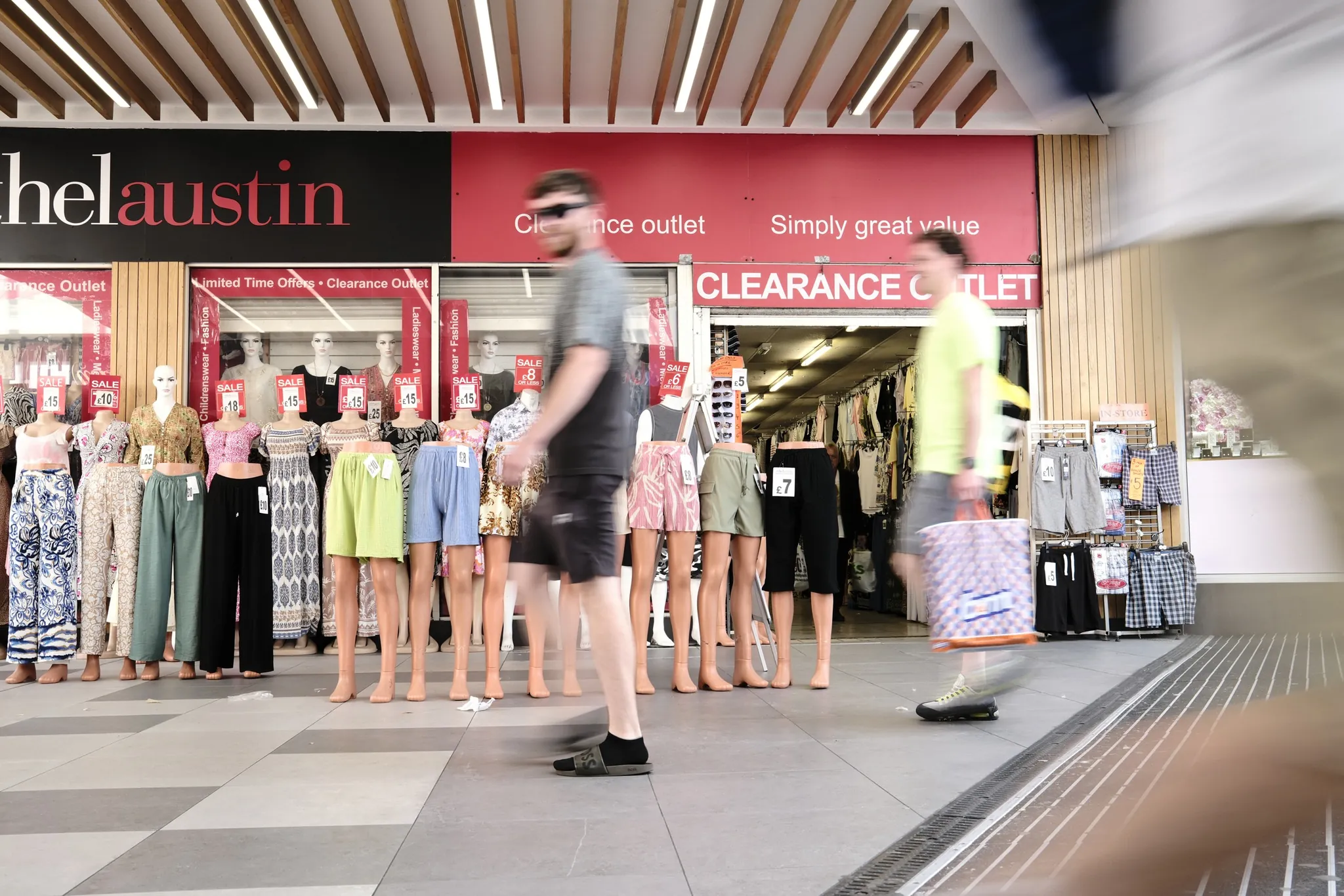 A blurred pedestrian crossing in front of a clothing shop window.