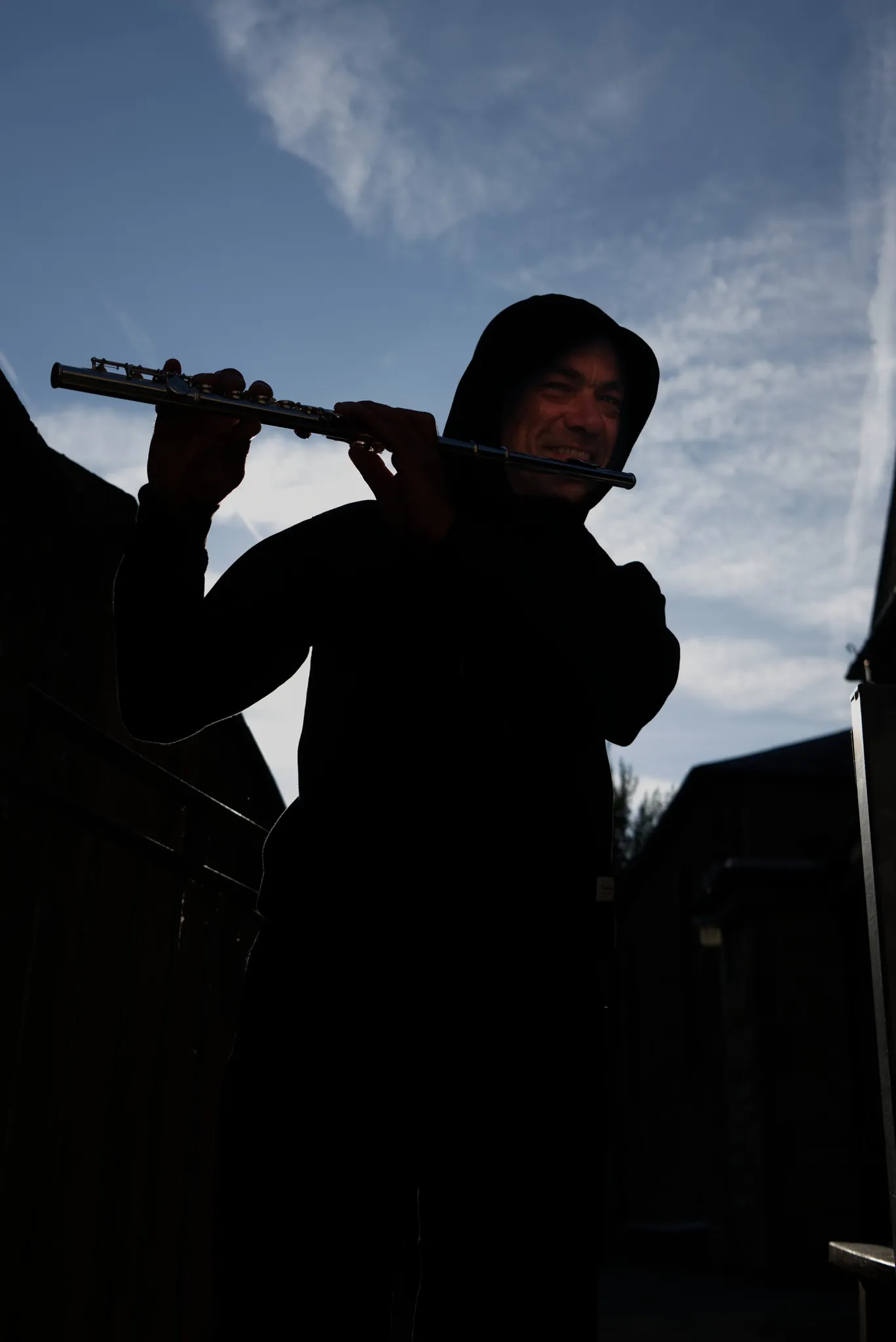 A musician holding a flute against a bright sky.