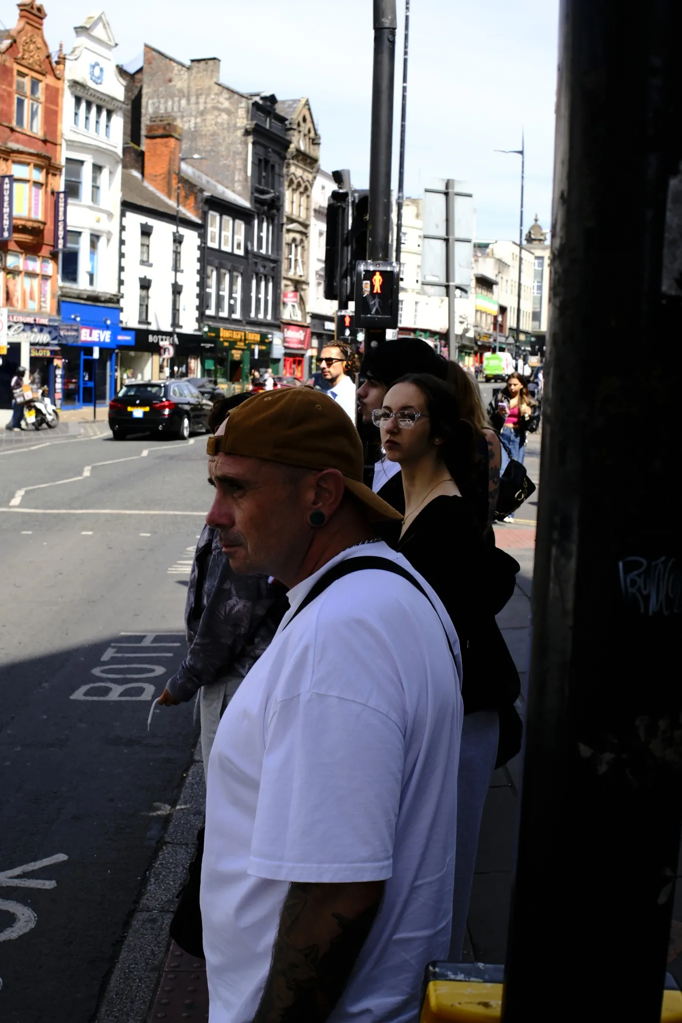 Pedestrians gathered beside a busy city street.