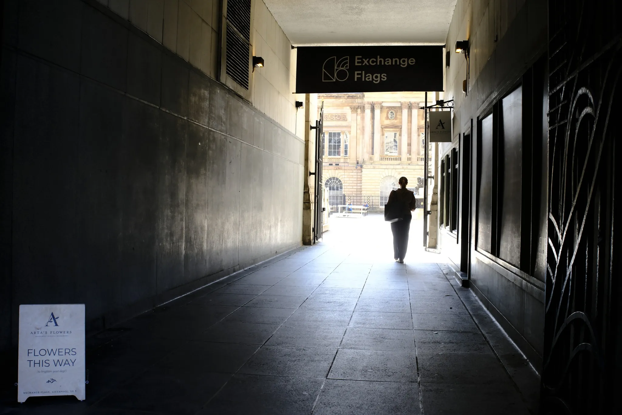 A figure walks through a dark passage towards Exchange Flags and the rear of Liverpool Town Hall.