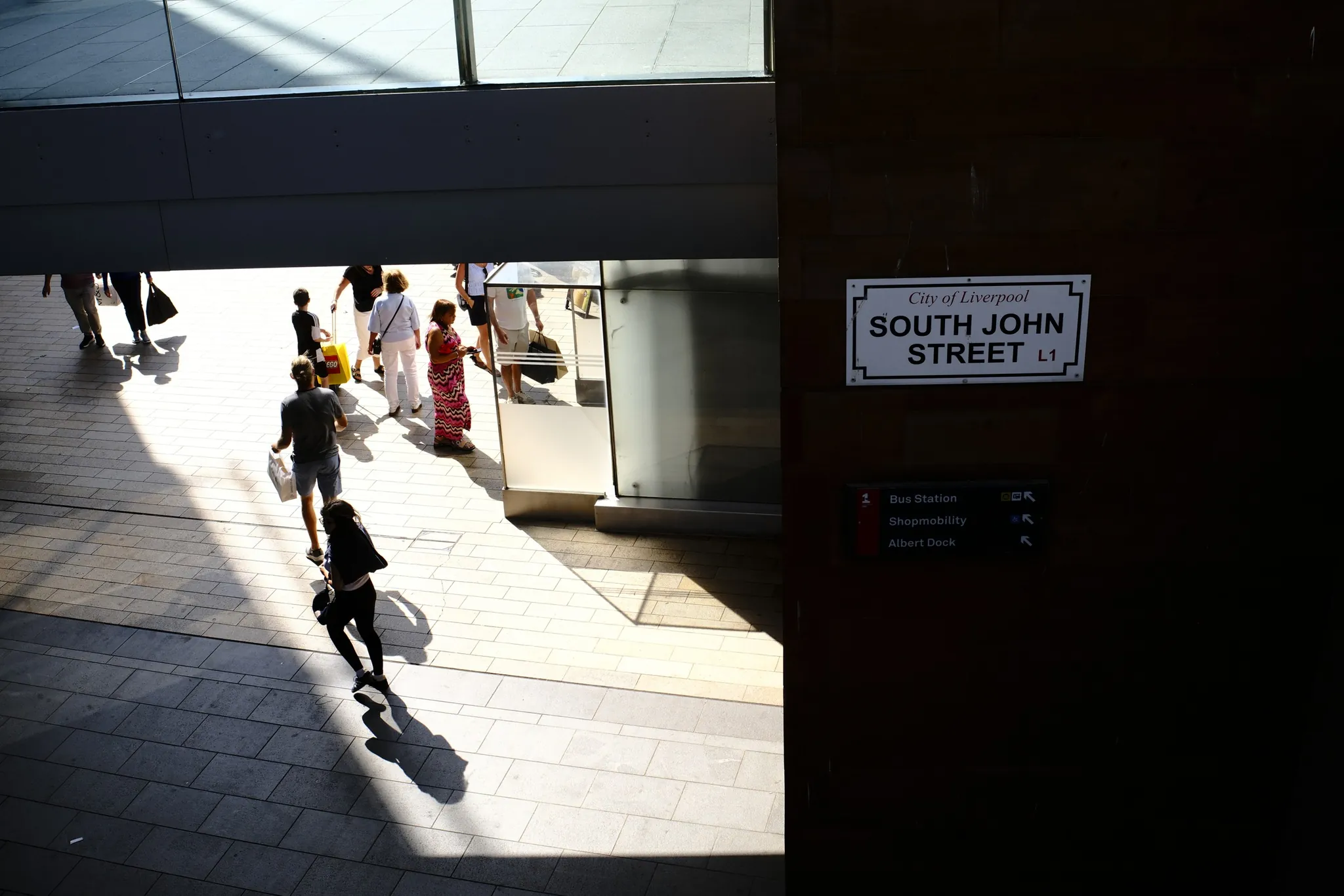 An elevated view captures pedestrians and long shadows on South John Street at Liverpool ONE.
