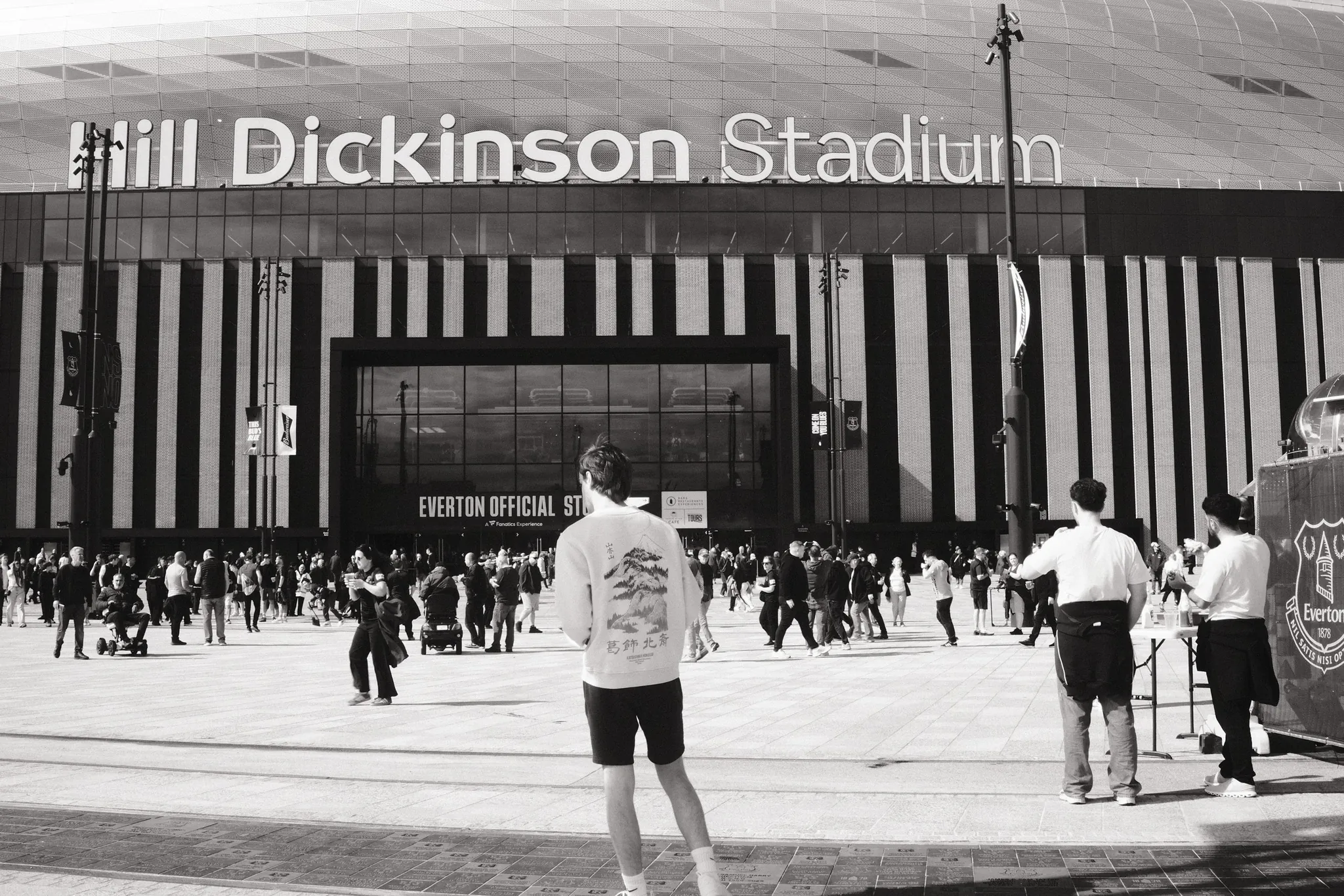 Supporters gathering outside Everton’s stadium, in black and white.