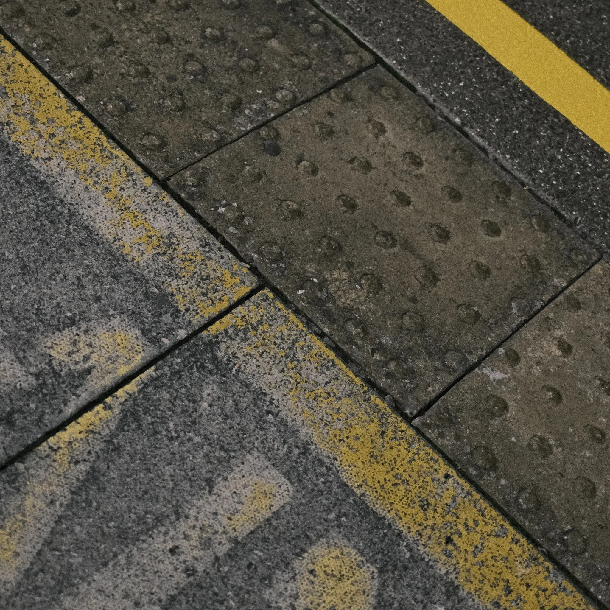 Yellow safety markings and tactile paving at a railway platform edge.