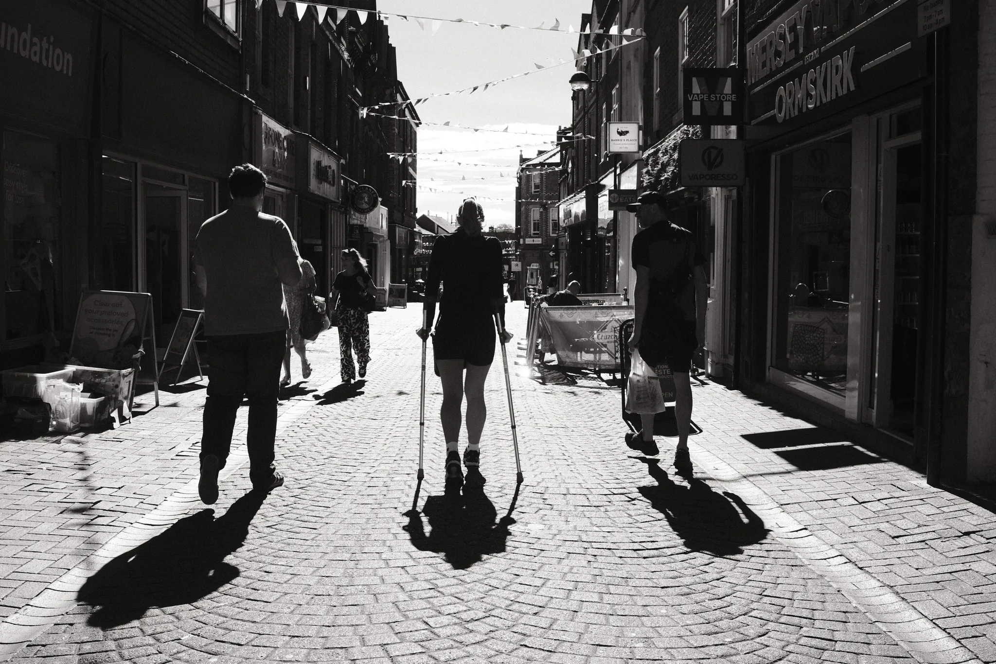 Pedestrians cast long shadows along Burscough Street towards Ormskirk Clock Tower.