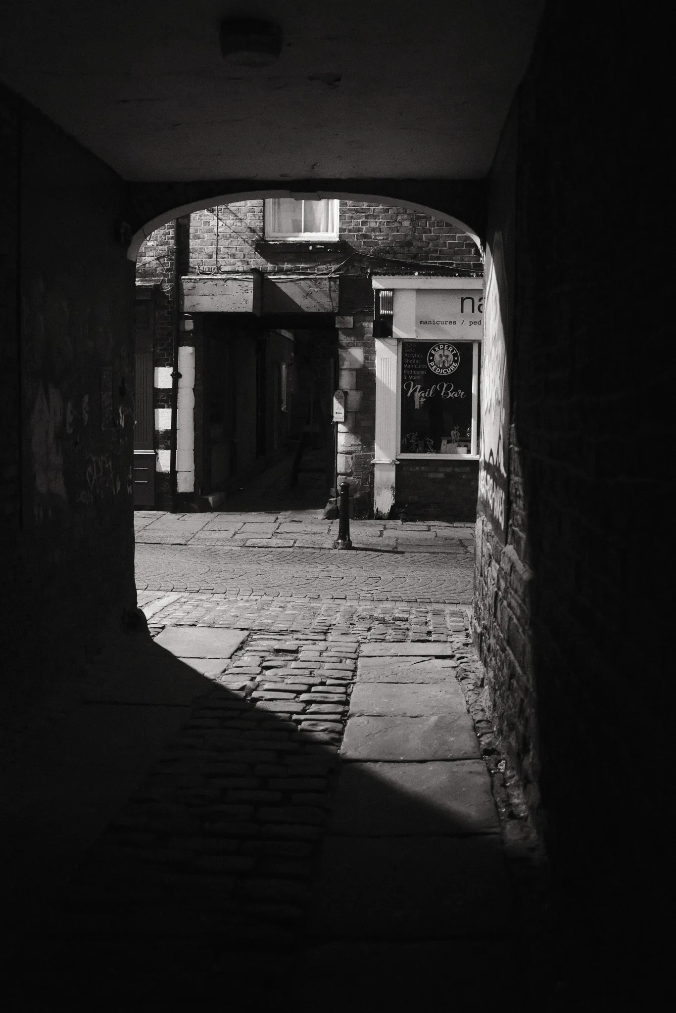 A shop doorway seen from the darkness of a narrow passage.
