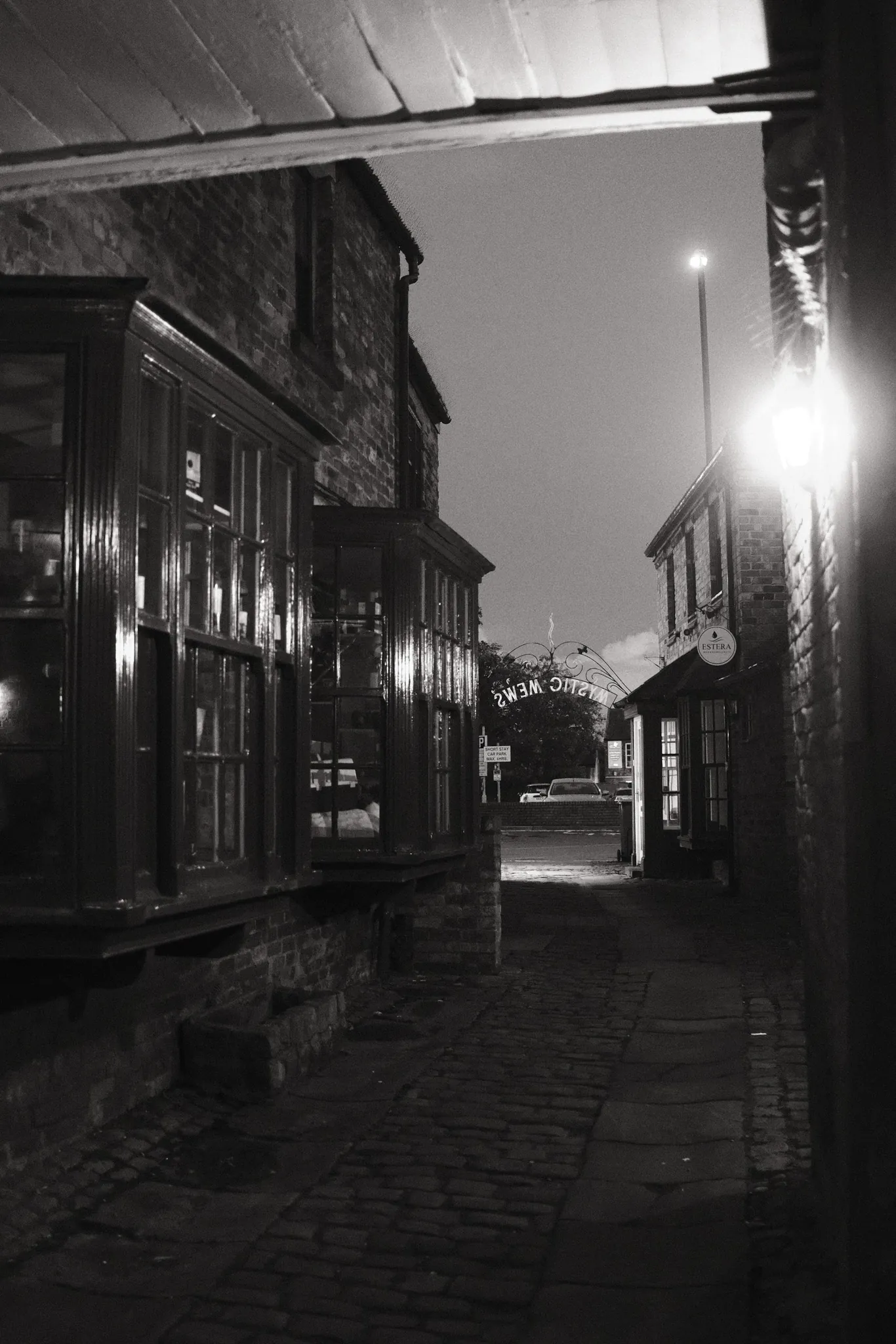 Shopfronts and the Mystic Mews arch are lit after dark in Ormskirk.