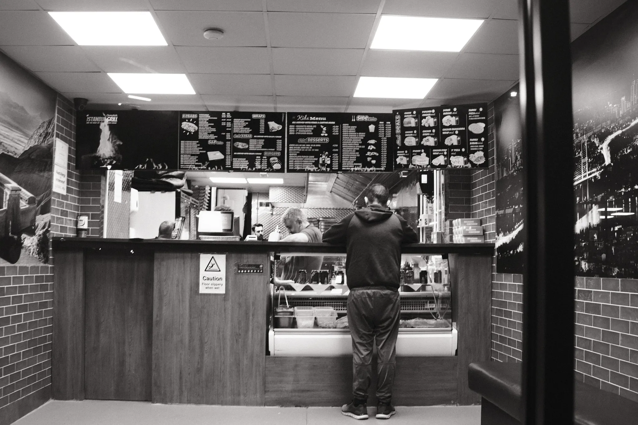 A person standing at an illuminated takeaway counter.