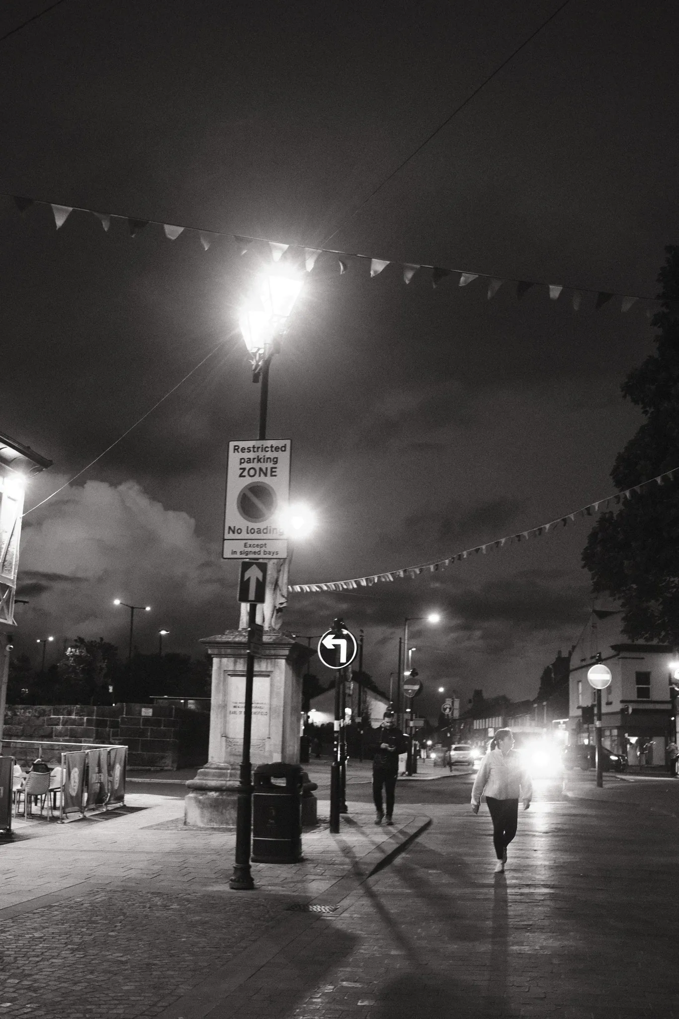 Street lamps and headlights illuminate Moor Street beside the Golden Lion and Disraeli statue.
