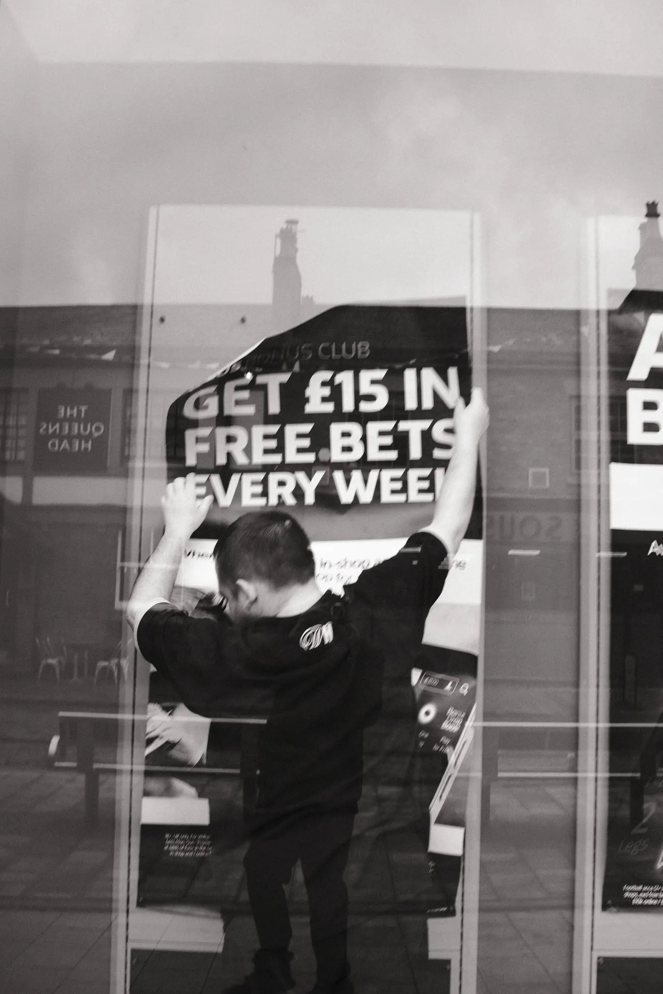 A reflected figure overlaid with lettering in a shop window.