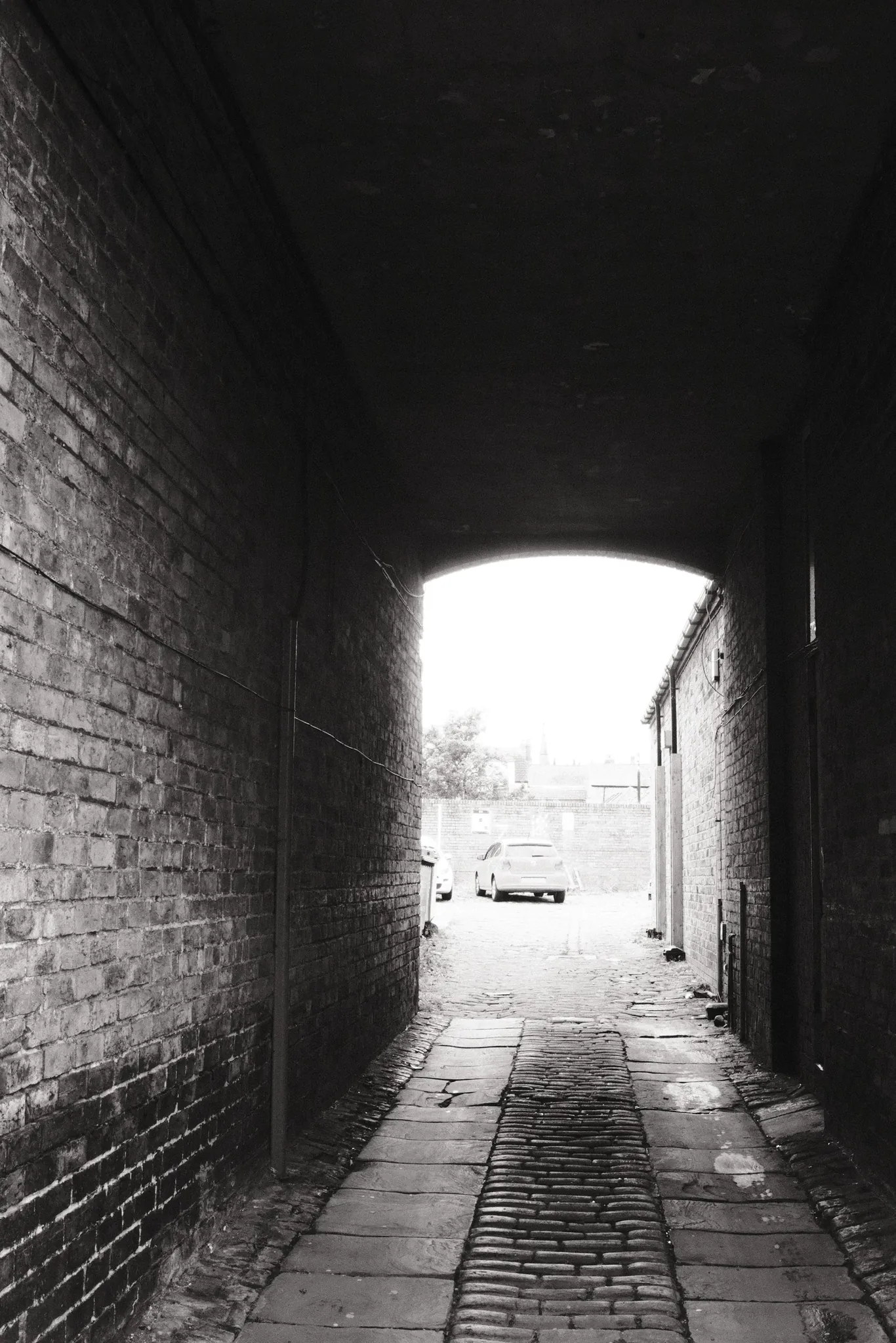 Daylight at the far end of a narrow brick passage.