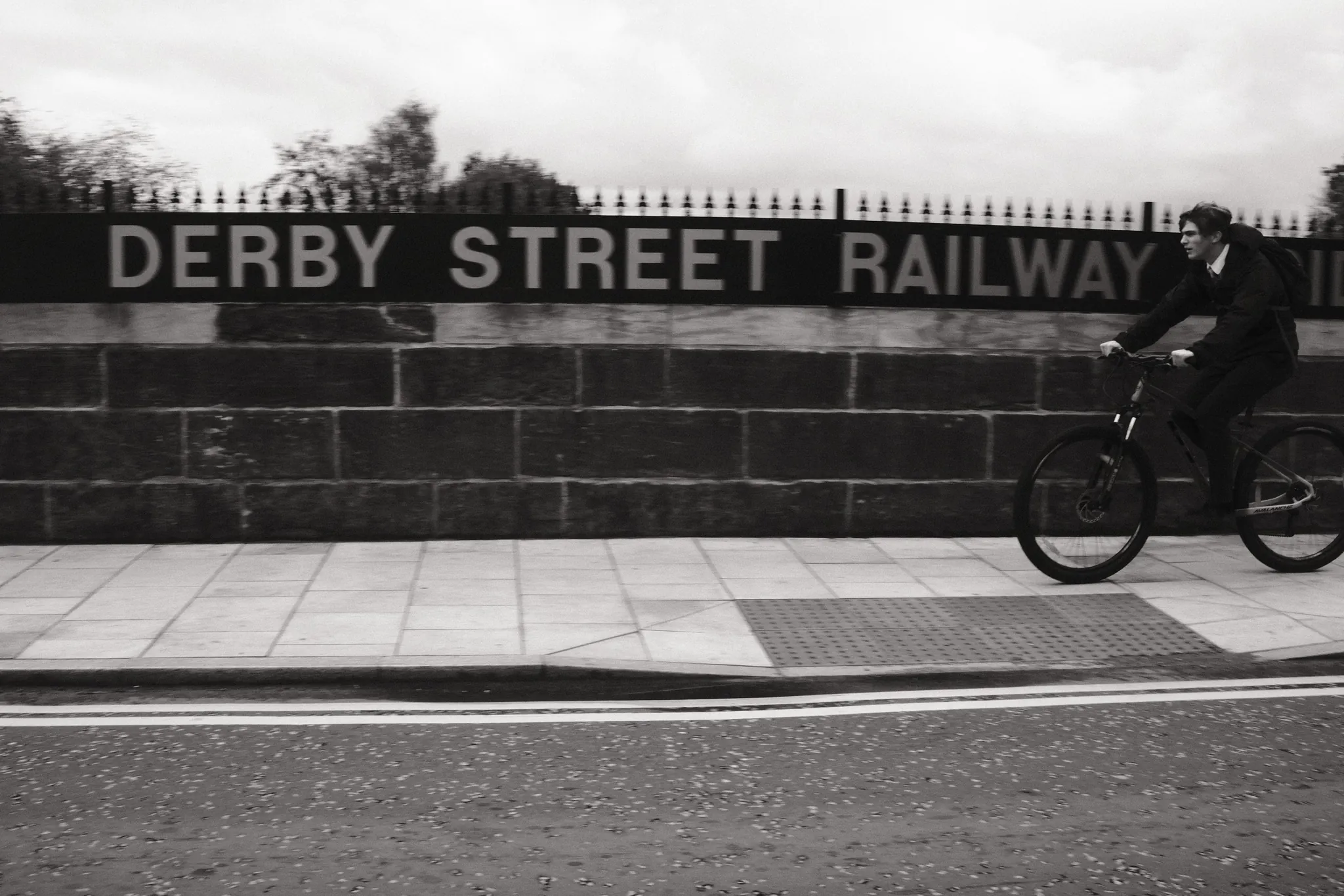 A cyclist passes the carved Derby Street Railway lettering in Ormskirk.