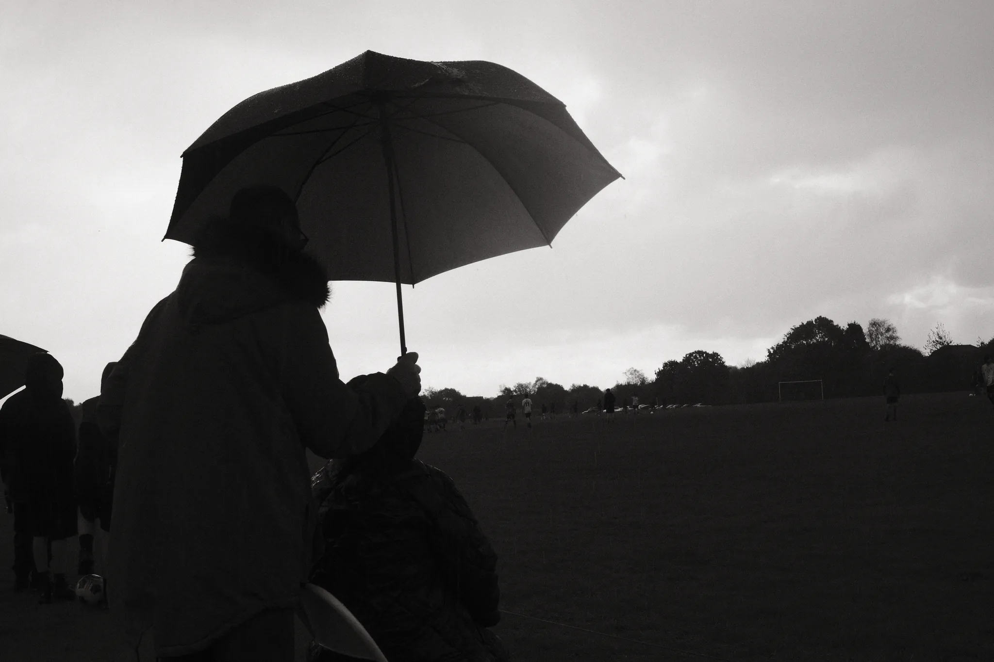 An umbrella and its holder form a dark silhouette against an overcast sky.