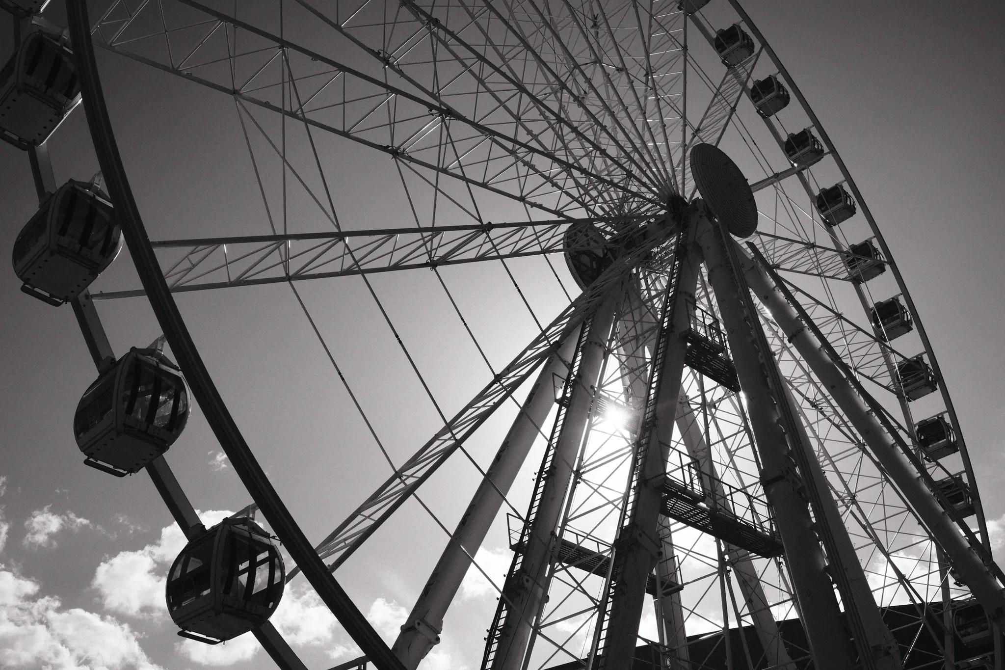 The spokes and passenger cabins of an observation wheel spread across the sky.