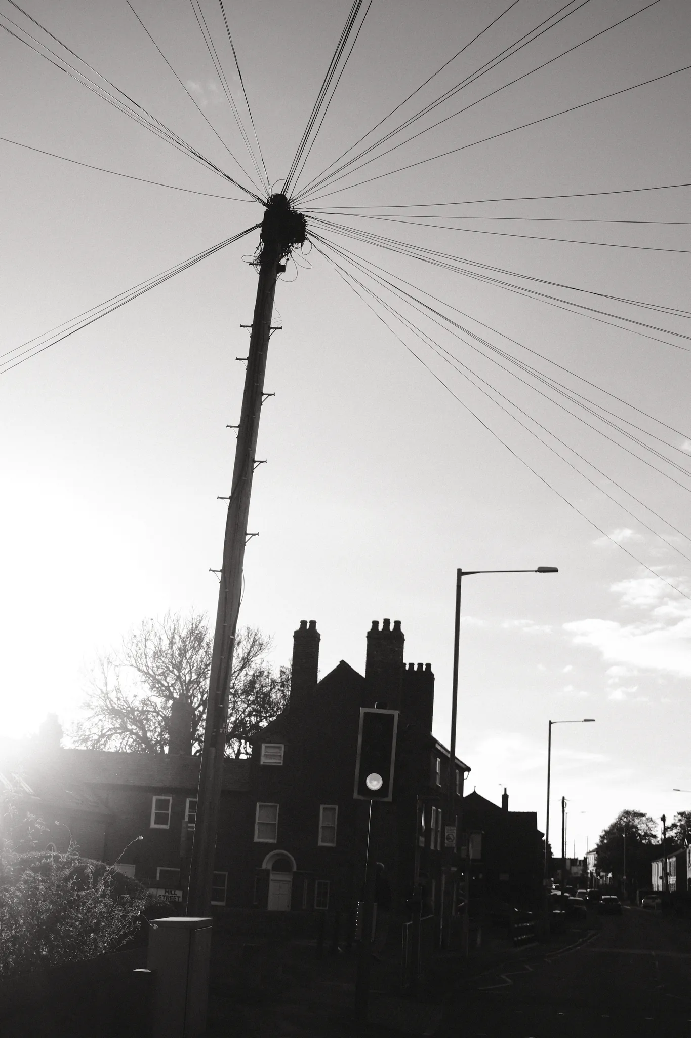 Overhead wires radiate from a pole above silhouetted rooftops.